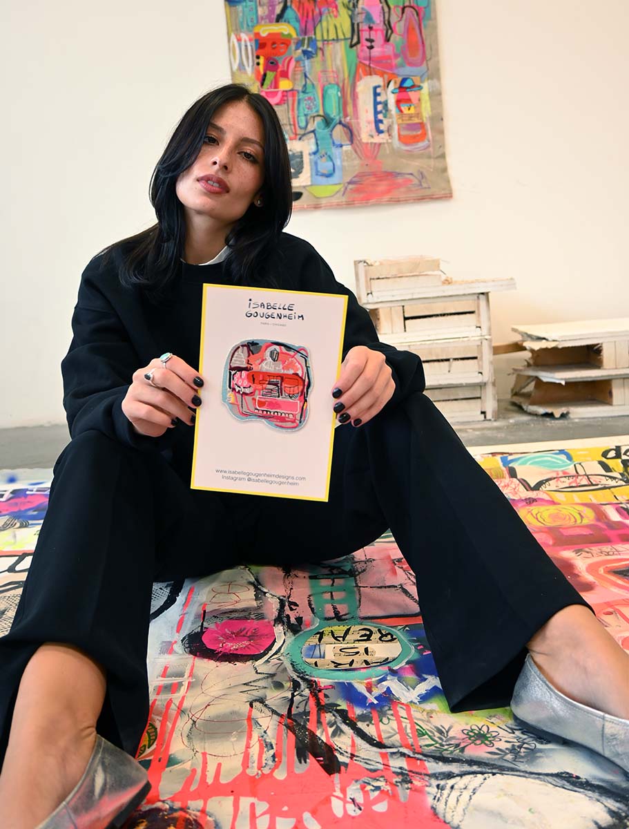 Person holding a book in an art gallery with colorful artworks on the walls and floor.