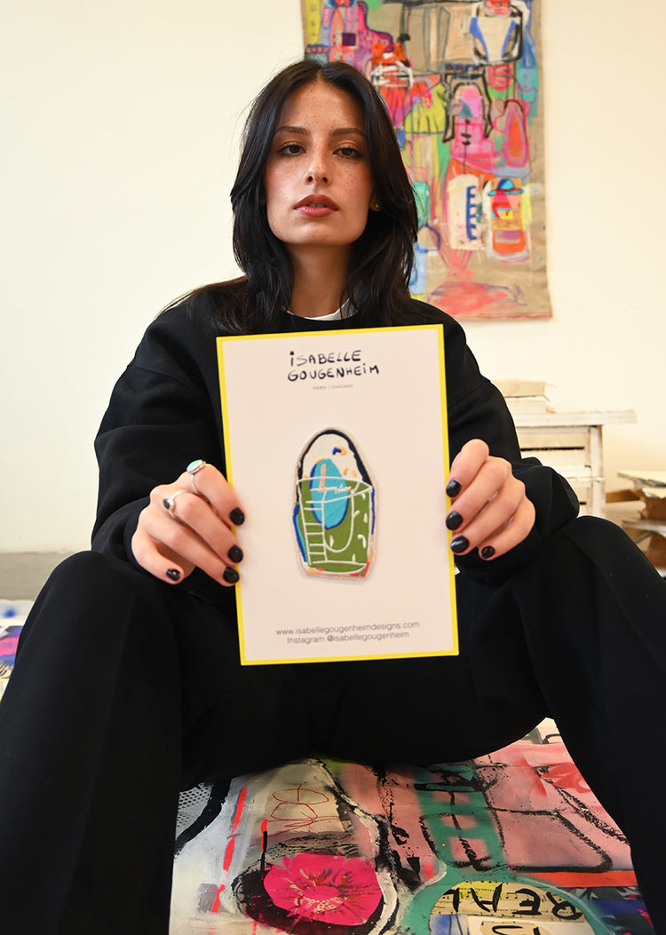 Person holding a card with a colorful bag design in an indoor setting