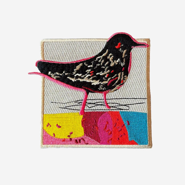 Embroidered patch with a colorful bird design on a white background