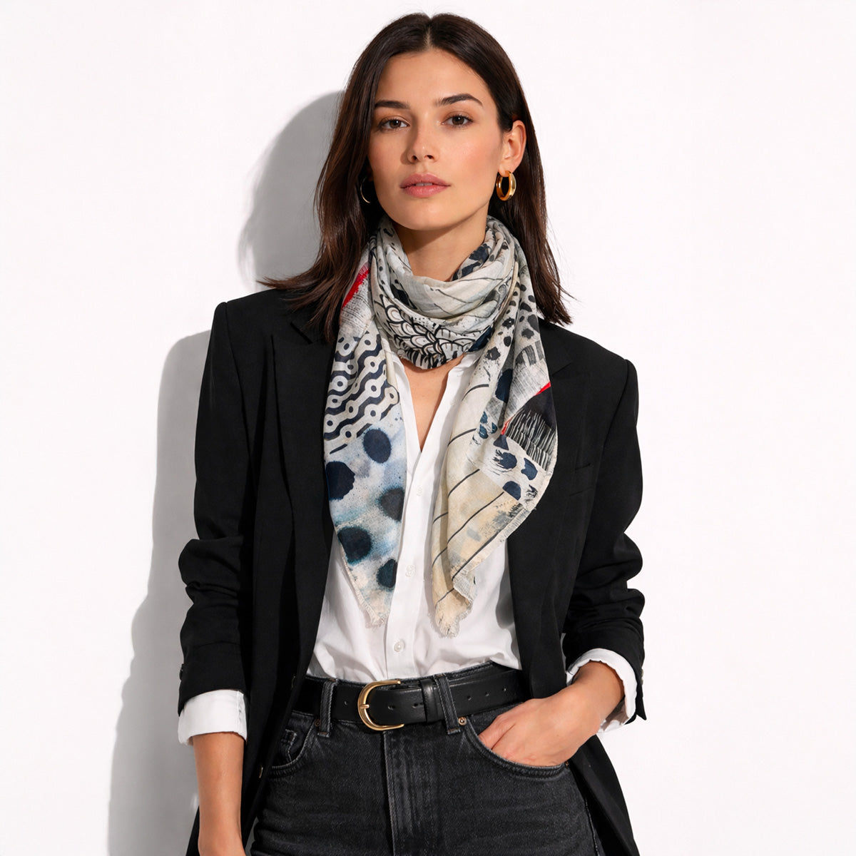 Model wearing the C’est La Vie Silk Scarf by Isabelle Gougenheim wrapped around the neck, showing its black, cream, blue and red abstract design.
