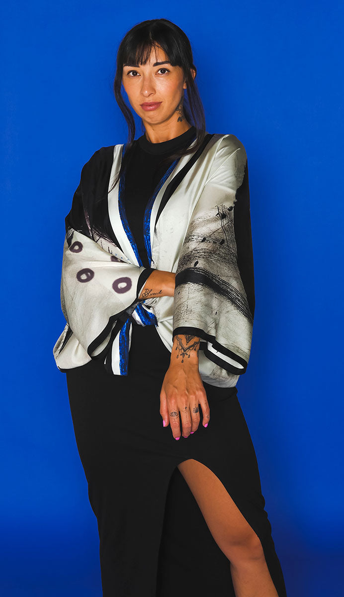 Woman wearing a stylish outfit with a black and white patterned jacket against a blue background