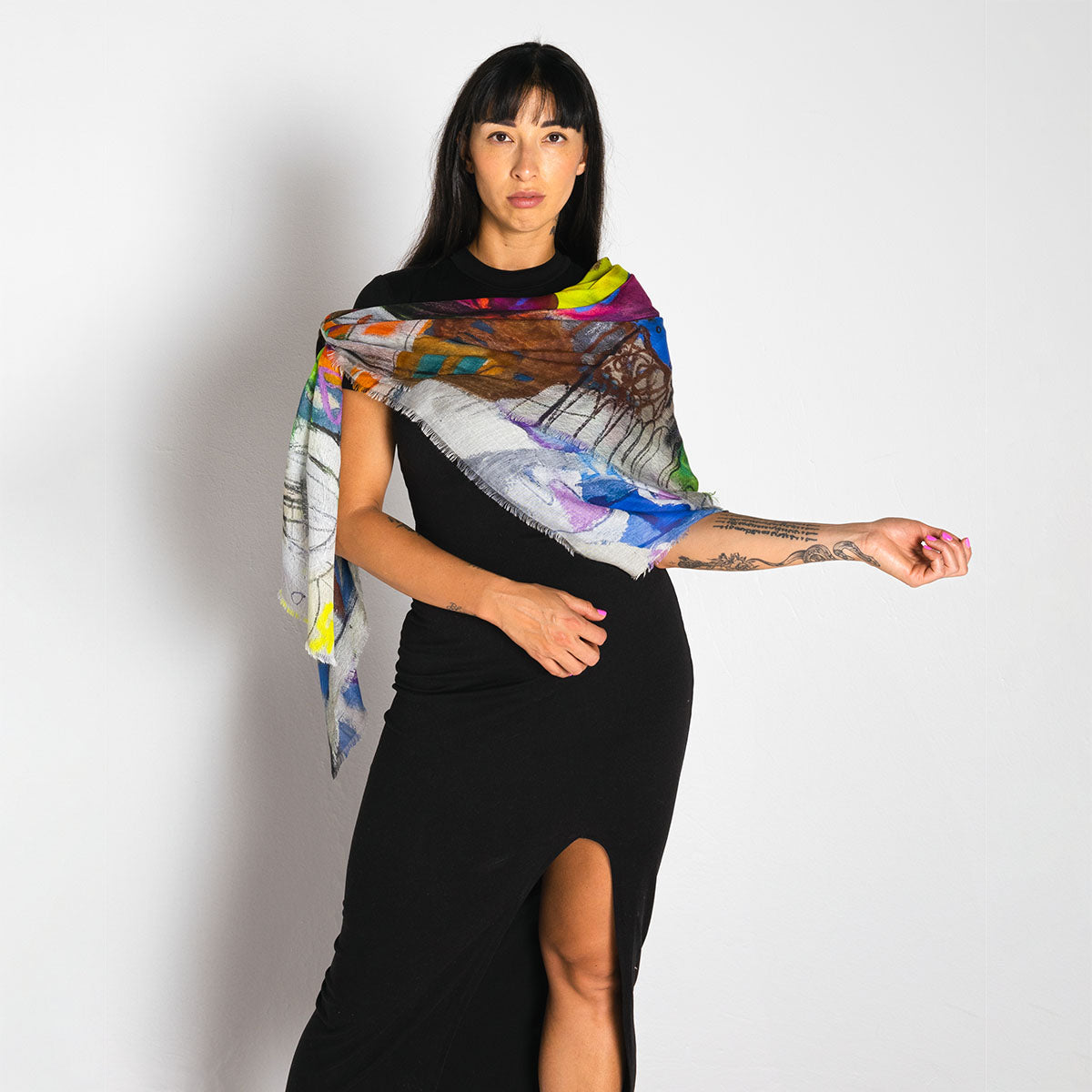 Woman wearing a colorful scarf with artistic design on a plain background