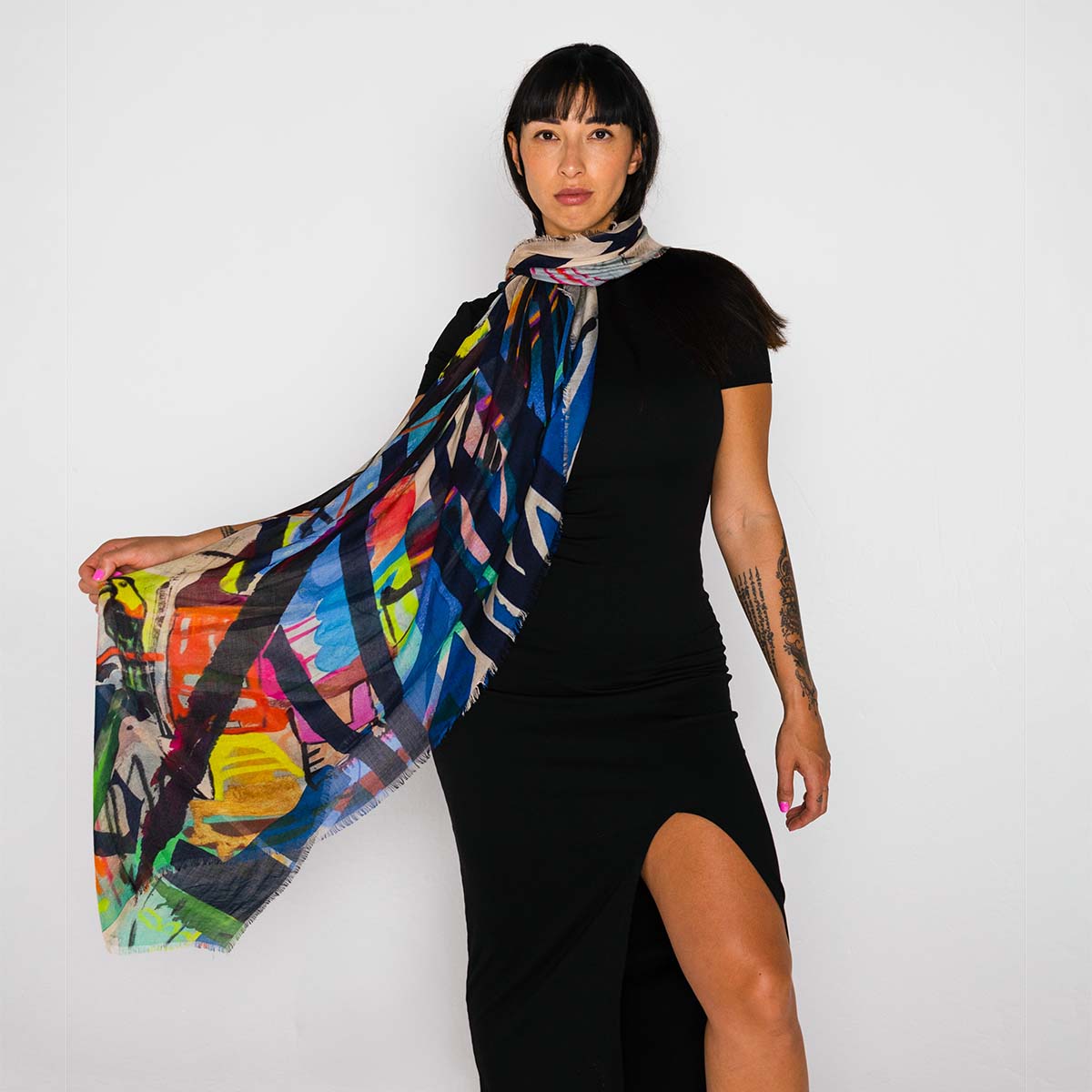 Woman wearing a black dress with a colorful scarf draped over her shoulders against a white background